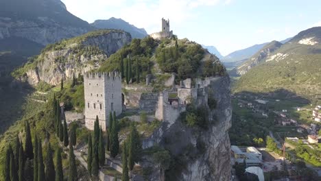 zoom out drone shot in 4k of an old castle fortress on top of a hill mountain cliff side, arco, riva del garda, trentino