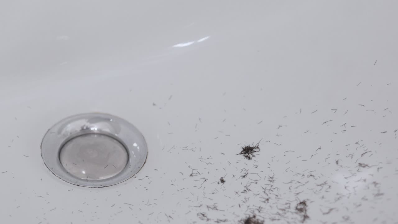 면도하는 동안 흰색 욕실 세면대에 떨어지는 수염