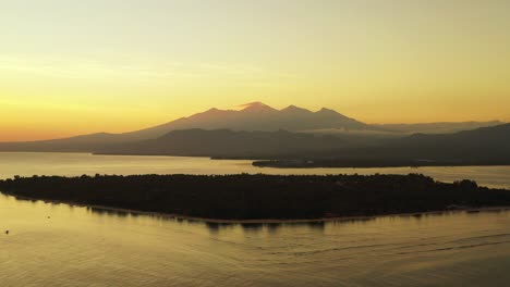 magic colors of sky after beautiful sunset with yellow glowing horizon over mountains reflecting on sea around silhouette of tropical island, bali