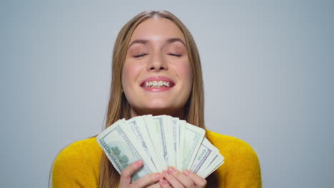 retrato de una mujer joven sonriente contando dinero en un fondo gris en el estudio.