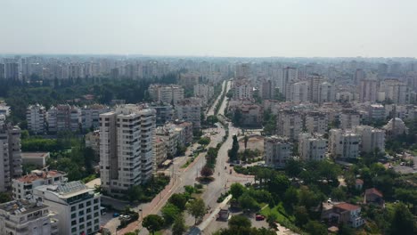 Drone-Aéreo-Que-Pasa-Por-Una-Carretera-En-El-Centro-De-Antalya,-Turquía,-A-Lo-Largo-De-La-Costa-Del-Mar-Mediterráneo-En-Un-Soleado-Día-De-Verano-Rodeado-De-Altos-Edificios-De-Apartamentos-Residenciales