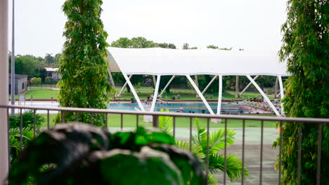 balcony view overlooking lush trees and contemporary public swimming pool