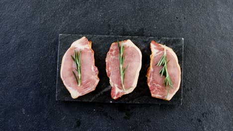 Three-raw-sirloins-arranged-on-the-board-with-rosemary