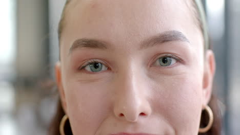 close-up of woman with blue eyes and hoop earrings looking at camera