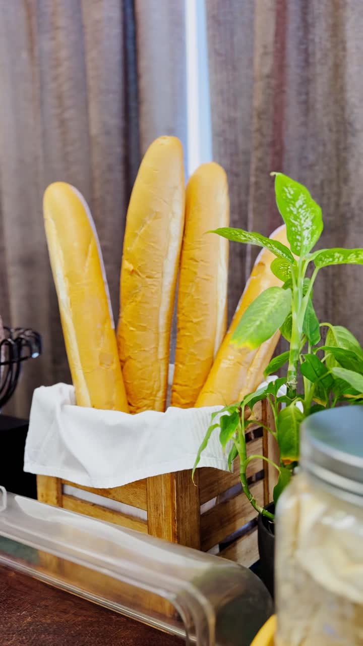 Golden French baguettes stand tall in a wooden crate wrapped with a white cloth, perfect for bakery, restaurant, or breakfast visuals. Clean, rustic, and vertical 4K food display.