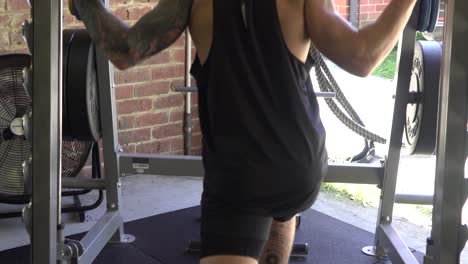 hombre musculoso en el gimnasio en casa haciendo ejercicio tiro desde la parte posterior de la pantorrilla levantando la máquina smith