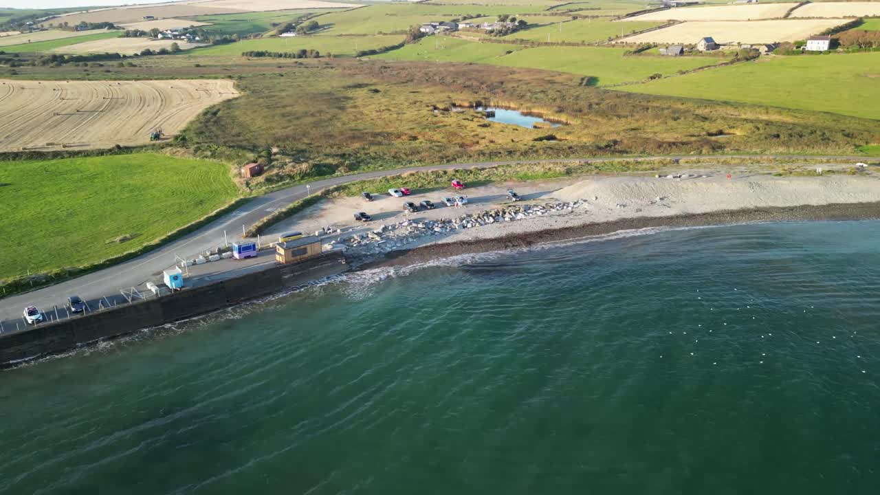 Coastal road aerial view and waves on a sandy beach, Garretstown, county Cork, Ireland on a sunny day, surfers and camper vans