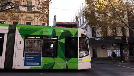 green tram moving through city street