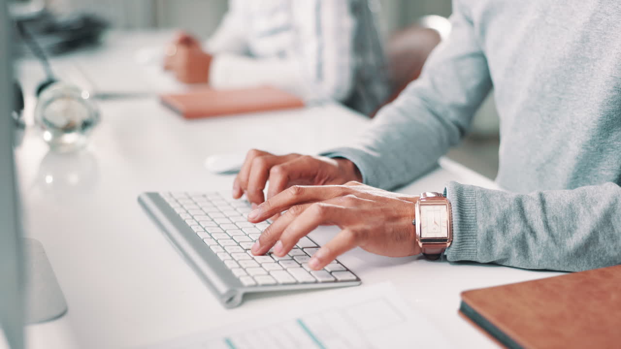 Typing on a computer keyboard at a desk in an office