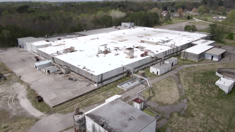 Aerial-Drone-Footage-Orbiting-Around-an-Abandoned,-Decaying-Factory-Surrounded-by-a-Forest