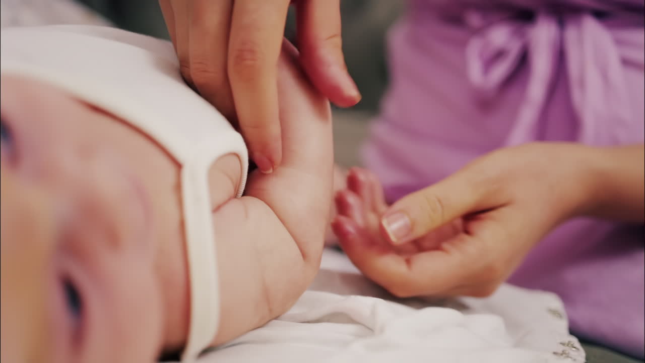 Close up of a parent's hands massaging a baby's hands and arms