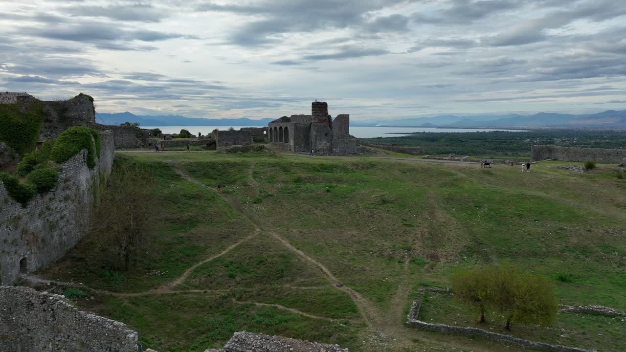 Antiche rovine a Scodra con ampi campi verdi e montagne distanti sotto cieli nuvolosi