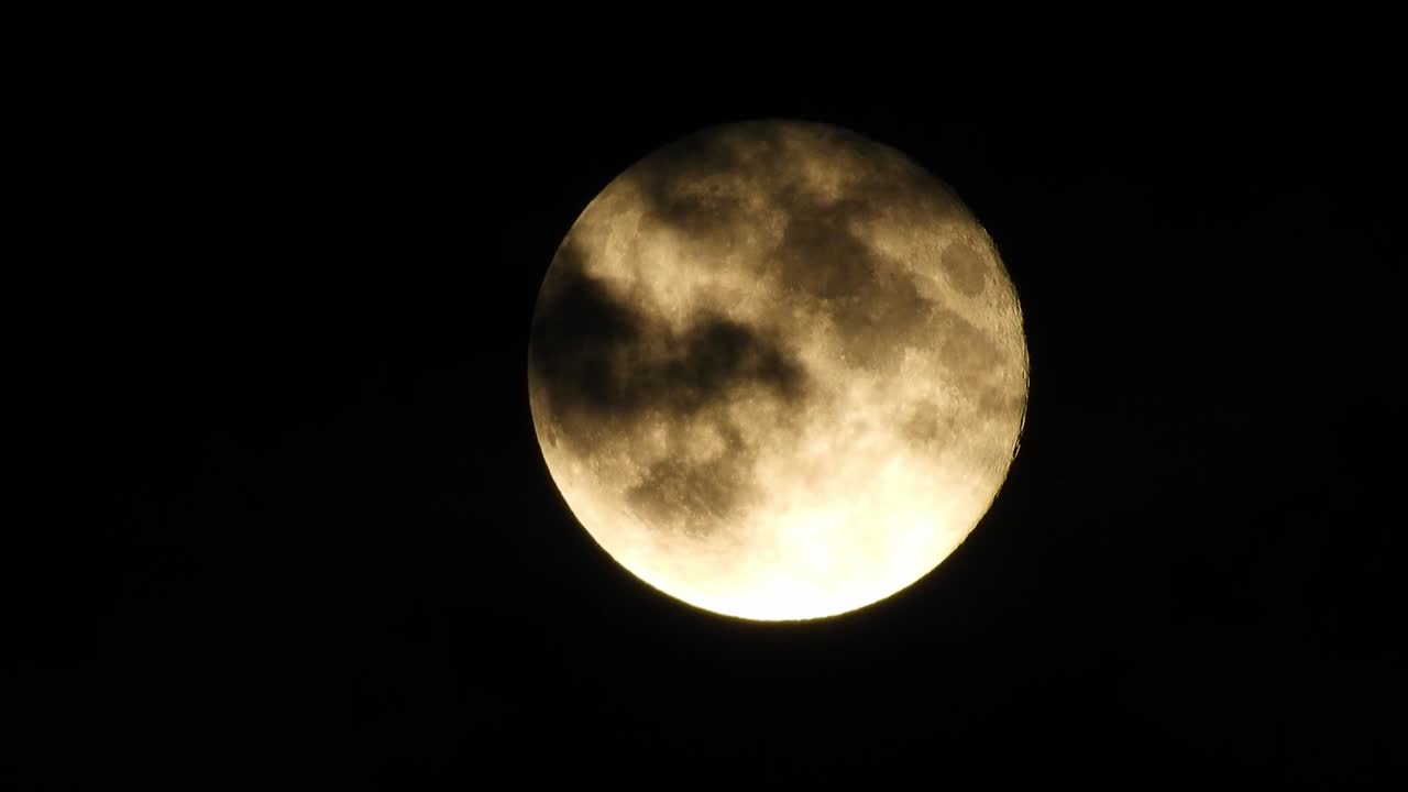 Moon at night with cloud real time. 4k video moon in the black sky.  Clouds passing by moon at night. night sky with cloudy weather