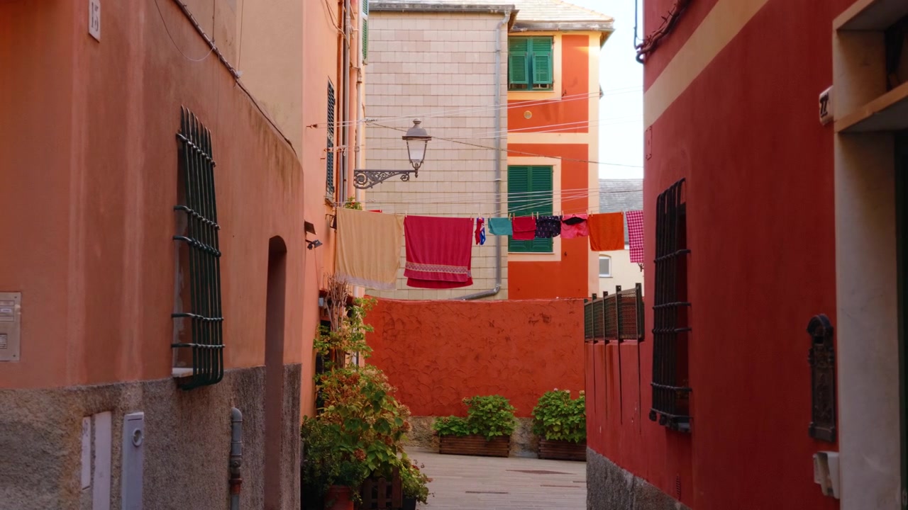 Vicolo stretto e colorato con bucato steso tra case tradizionali a Genova