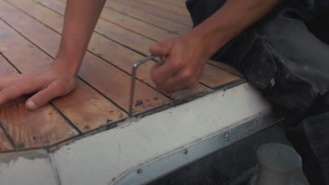 raspado de sellador de masilla viejo entre el entarimado del techo de un barco de madera