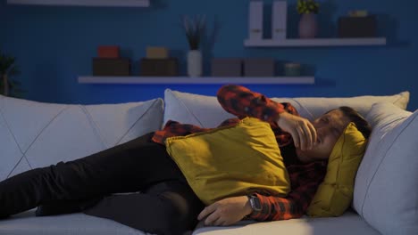 The man lying on the sofa is crying.
