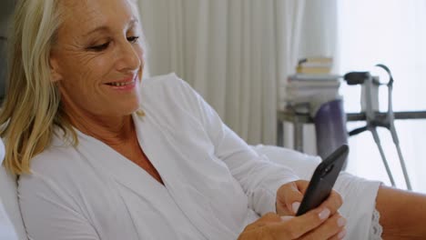 mujer discapacitada usando teléfono móvil en el dormitorio 4k