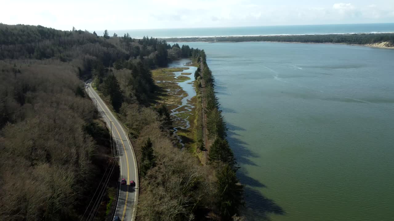 US, Oregon, Garabaldi, Nehalem Bay, 2025-03-18 - Drone view over the railroad along Nehalem Bay with the Pacific Ocean in the distance. The railroad is on a berm.