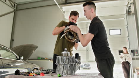 dos técnicos reparando una transmisión de un vehículo eléctrico