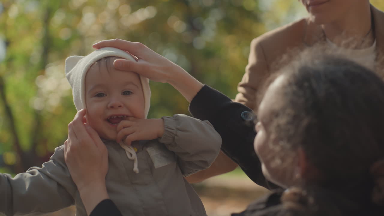Kærlige familiemomenter. Generationer deler varm hengivenhed. En ægte scene med familiesammenhold i løbet af en eftermiddag i sæsonen. En hjertevarm familiescene der fanger ømhed og omsorg i parken om efteråret.