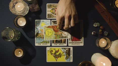 overhead shot of person giving tarot card reading laying down cards on table with candles and crystals 2