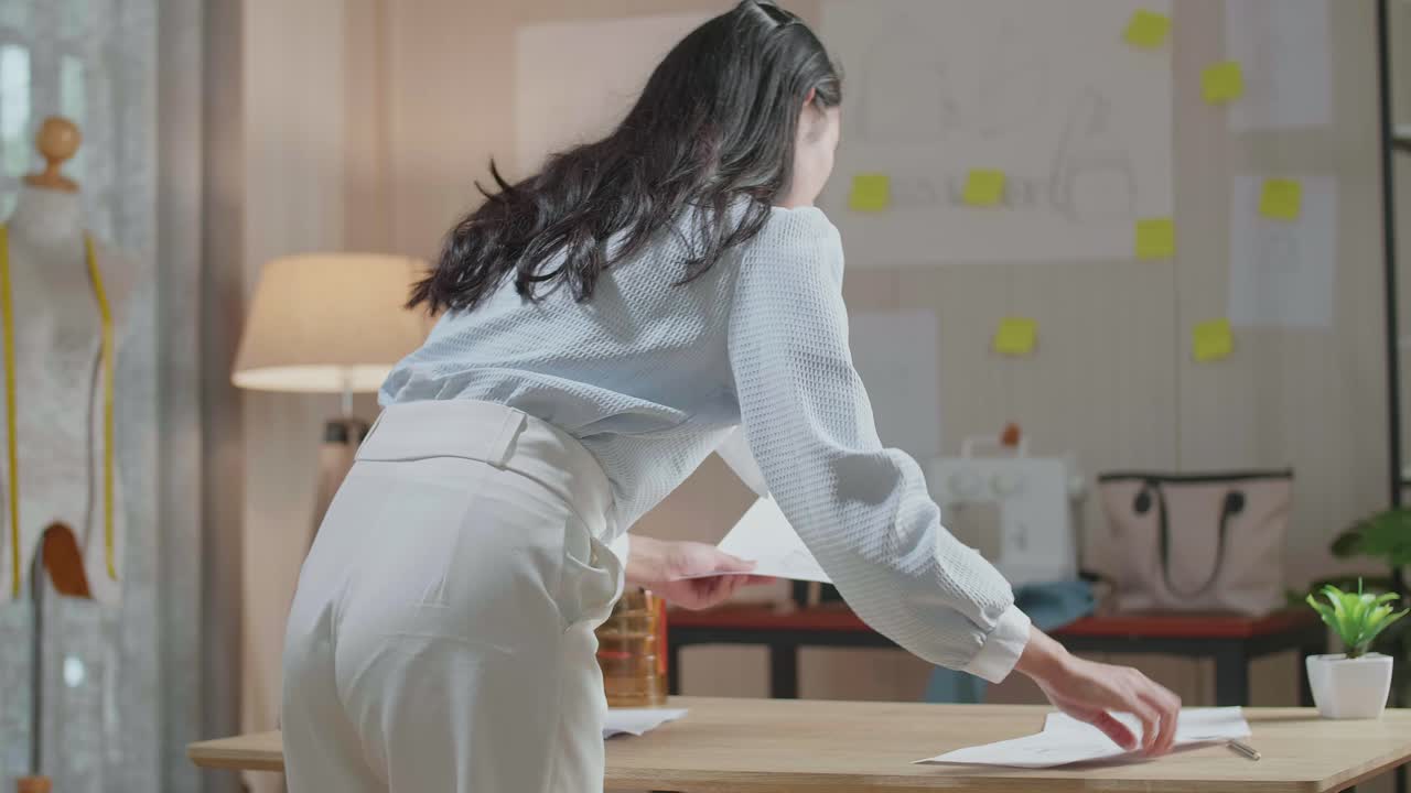 vista trasera de una mujer diseñadora arreglando la bolsa dibujando el diseño del enlace en la oficina