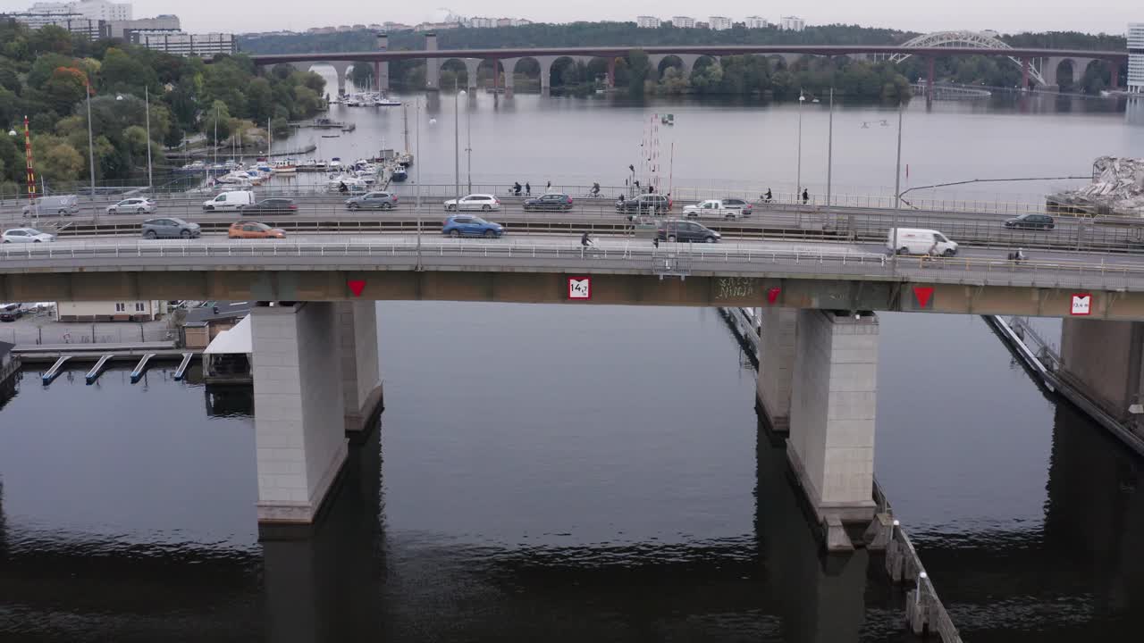 Cars, cyclists and pedestrians going over canal during rush hour on bridge in S&ouml;dermalm, Stockholm, Sweden during cloudy evening