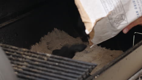 charcoal briquettes being poured in to bbq pit smoker before grilling