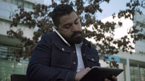 Bearded man using smartphone and tablet pc outdoor