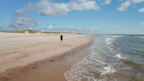 Seguimiento-De-Persona-Activa-En-La-Playa.-Corriendo-Sobre-La-Arena-A-Lo-Largo-De-Las-Olas-Lavando-La-Costa.-Lugar-De-Vacaciones-De-Verano.-Dinamarca