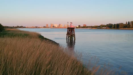 push-in fly-over drone shot of fields of grain with harbour entrance way and city filmed during golden hour