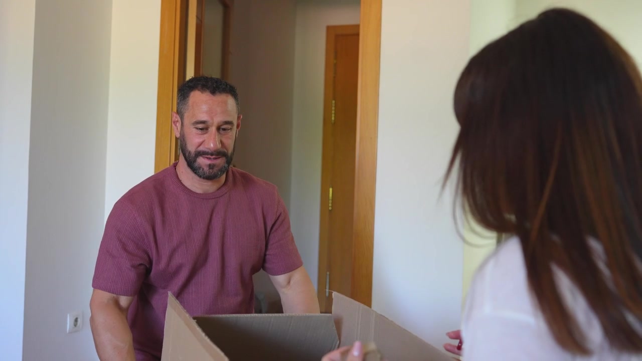 Marito e moglie che disimballano scatole di cartone dopo essersi trasferiti nel loro nuovo appartamento.