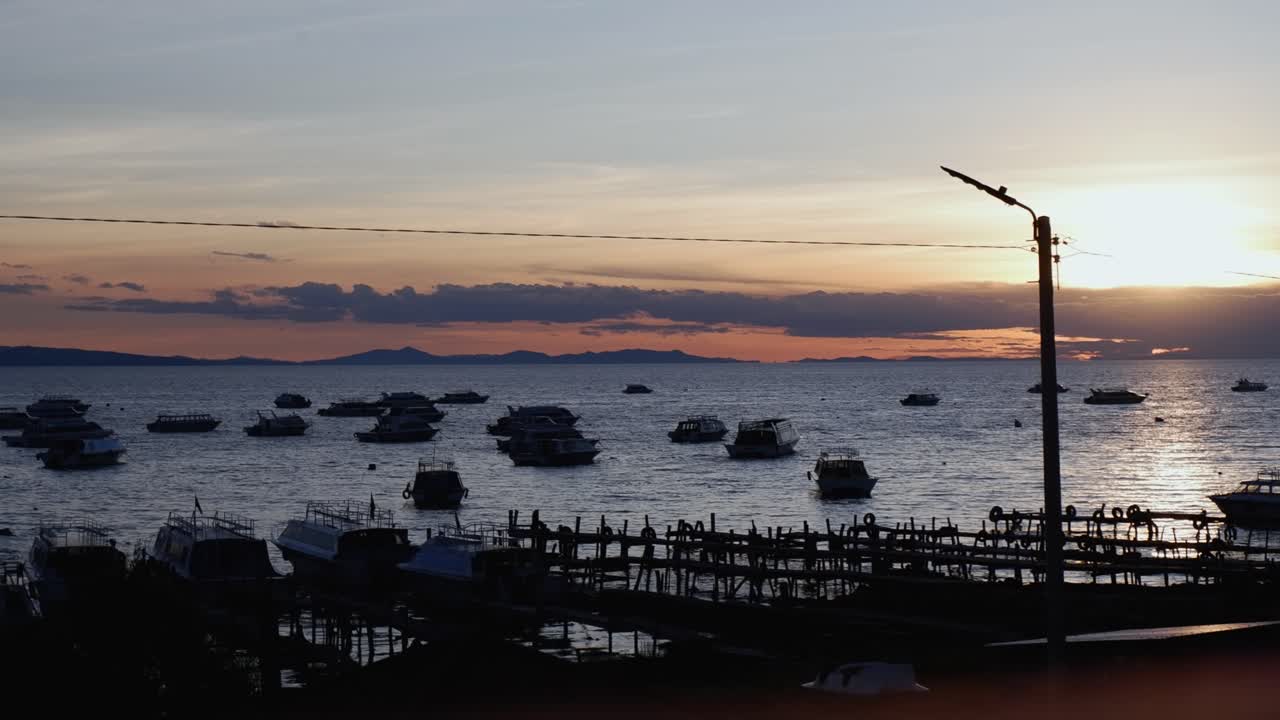 티티카카 호수에 있는 코파카바나 항구에 정박한 배 위에서 해가 뜨고 있다.