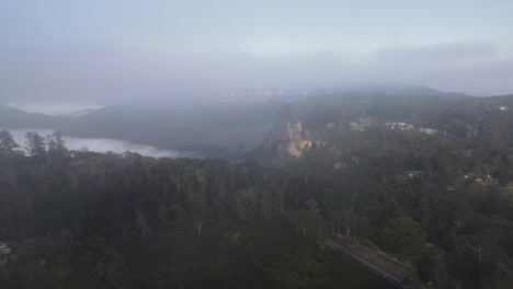 drone aerial moving forward through clouds showing the blue mountains on a cloudy morning