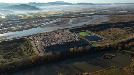 large landfill with unclassified waste on river bank, dangerous catastrophic ecological problem