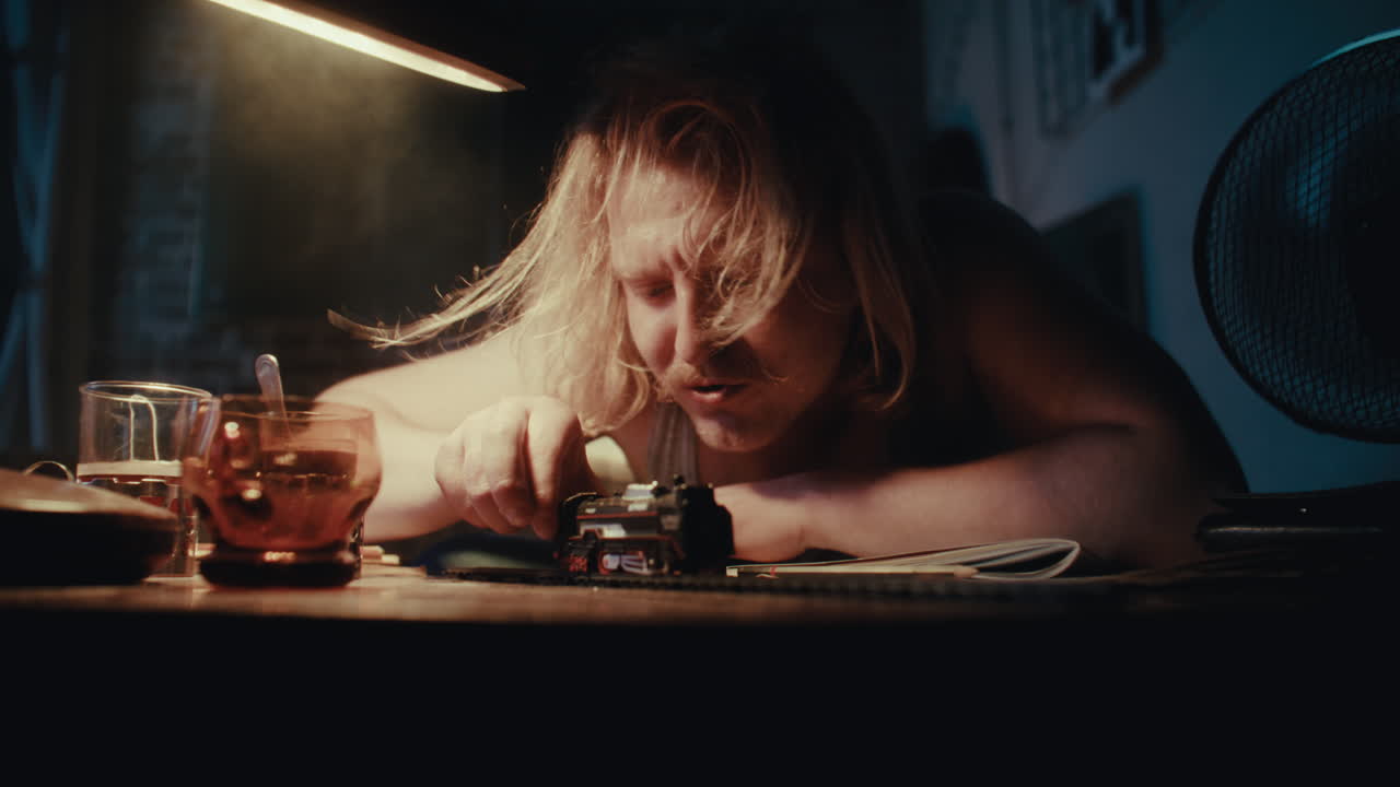 Man Working on a Model Train in a Dark Room