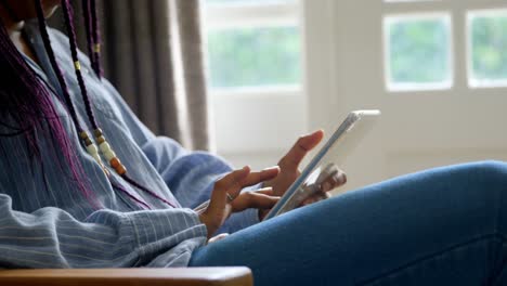 mid section of young black woman using digital tablet in living room of comfortable home 4k