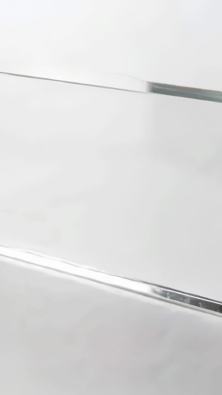 Vertical video: Moving camera filming shiny panel in room showing reflections and two metal strips
