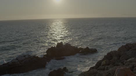 beautiful 4k backlit drone shot of atlantic ocean with rocky foreground reveal