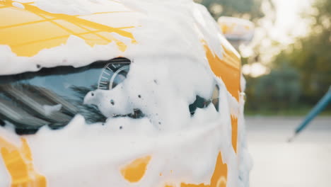 yellow car being washed with foam