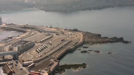 drone shot from far away over cirkewwa malta towards paradise bay