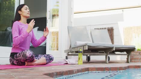 mujer biracial practicando yoga y meditando en el jardín