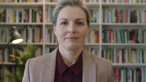 portrait of mature business woman executive looking at camera smiling confident enjoying successful corporate career proud female in library bookshelf background