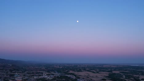 sky with moon over a sprawling landscape at the down as sunset in the opposite direction