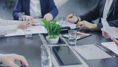 in the corporate meeting room close-up on the hands of businesspeople, signing contracts, using smartphones and digital tablet computers, gesticulating. people sitting at conference table