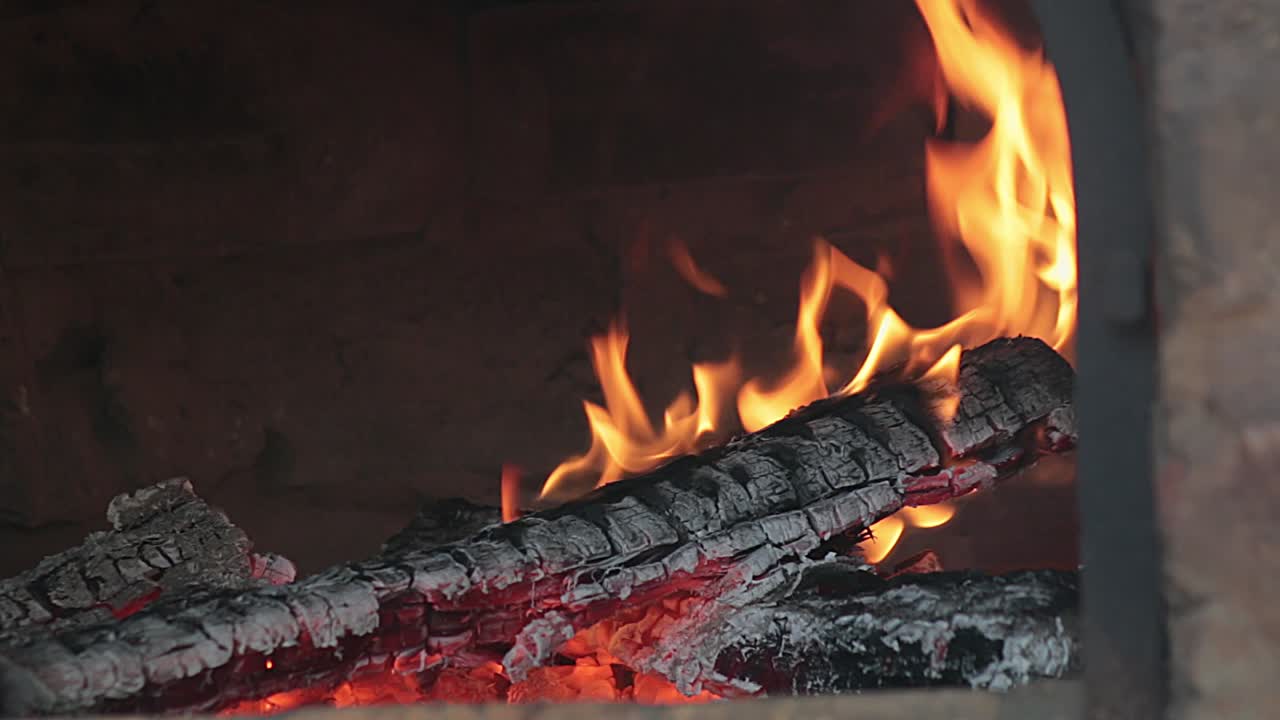 Firey burning wooden logs inside rustic pizza oven. Dying fire flames