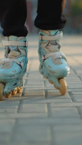 una vista de cerca de los pies de una persona que usa patines, deslizándose en un camino pavimentado en un parque. el enfoque en los patines hace hincapié en el movimiento y la actividad, con el fondo suavemente borroso