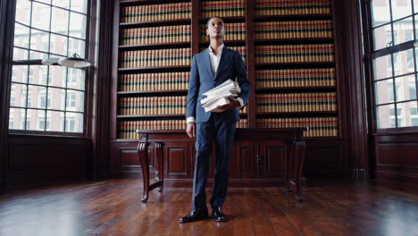 man in suit carrying books in a library