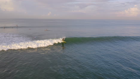 Vista-Frontal-De-Un-Surfista-Atrapando-Una-Pequeña-Ola-Y-Montándola-Durante-Algún-Tiempo