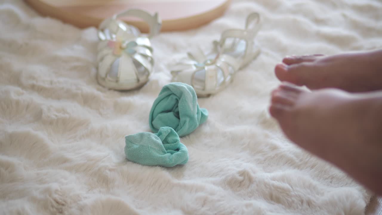 Child's Bare Feet Wiggling on a Fluffy White Rug with Socks and Sandals